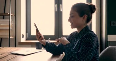 Hintli iş kadını elinde cep telefonu ile müşteriyle video arama uygulaması kullanarak konuşuyor