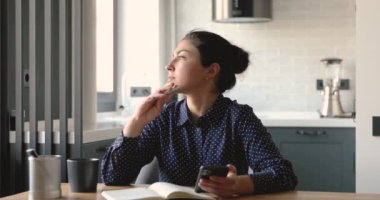 İş kadını cep telefonu internet çeviri uygulaması kullanıyor. Not defterine not alıyor.