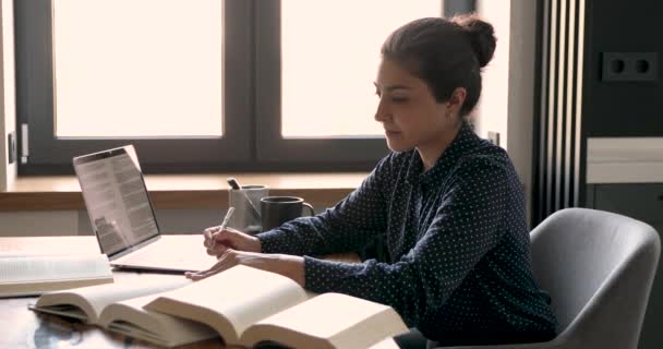Индийская студентка с помощью учебников готовится к экзаменам по написанию текста — стоковое видео
