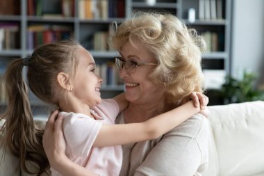 Gülümseyen olgun büyükanne ve küçük torunun kucaklaşması.