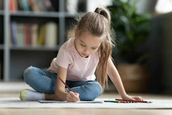 Mooi klein meisje spelen op warme vloer, tekening met potloden — Stockfoto