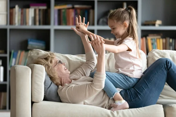 Feliz madura abuela jugando con poco nieta en sofá — Foto de Stock