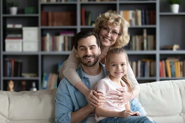 Семейный портрет улыбающейся бабушки, обнимающей взрослого сына и внучку — стоковое фото