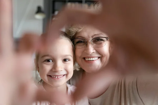 Fechar sorrindo avó e menina mostrando gesto do coração — Fotografia de Stock