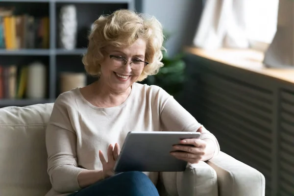 Sorridente donna matura con gli occhiali utilizzando tablet computer a casa — Foto Stock