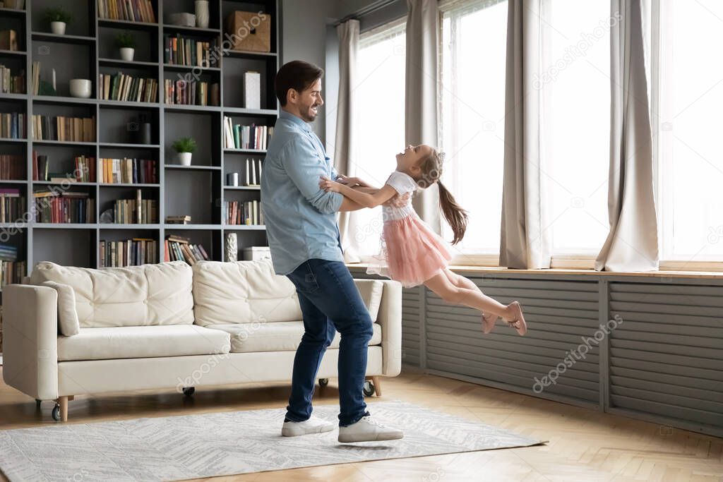 Loving father dancing with little daughter wearing princess dress