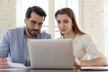 Birlikte laptopta çalışan meslektaşlar ekrana bakıyor, projeyi tartışıyorlar.