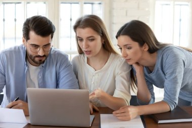 Birlikte proje üzerinde çalışan üç meslektaşım dizüstü bilgisayara bakıyor.