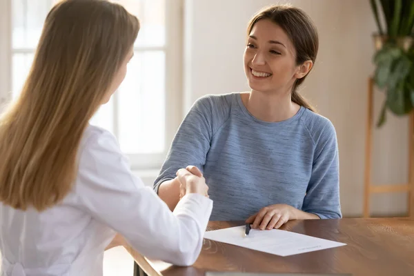 Smiling young woman shaking doctor hand, signing medical insurance contract — Stock Photo, Image