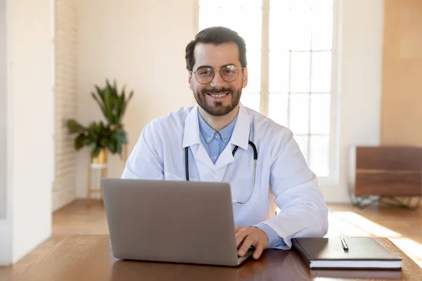 Hlava záběr portrét usměvavý lékař nosí brýle pracující na notebooku — Stock fotografie