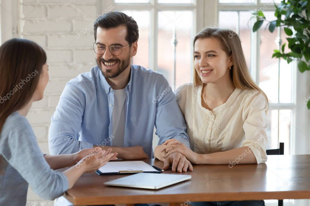 Happy young married couple listening to realtor advisor at meeting