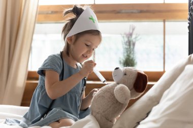 Kız elinde şırıngayla oyuncak hayvana iğne yapıyor.