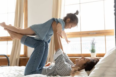 Anne kızını kollarının arasında tutuyor çocuk havada uçuyor.