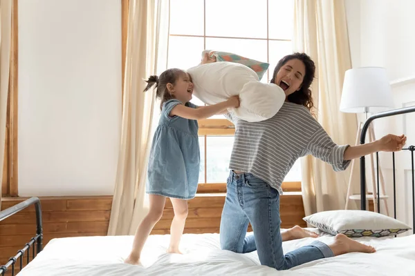 Mother daughter holds pillows fighting spend funny time in bedroom — Stock Photo, Image