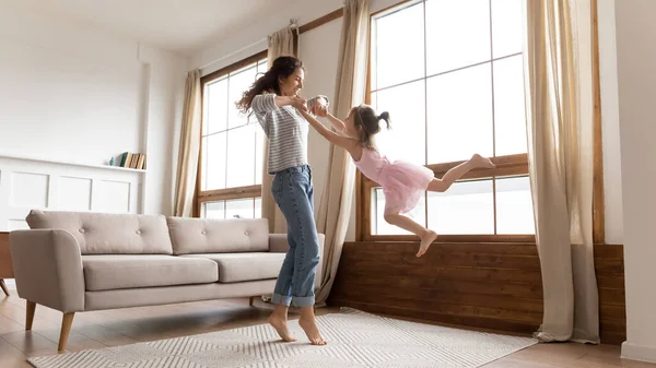 Happy mother spinning adorable little daughter playing in living room — Stock Photo, Image