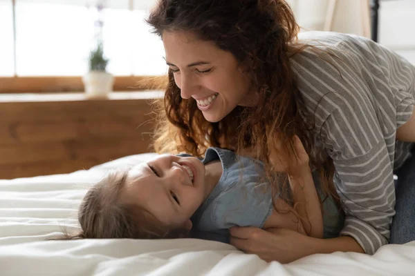 Mother cuddles tickles little daughter lying in bed feels happy — Stock Photo, Image