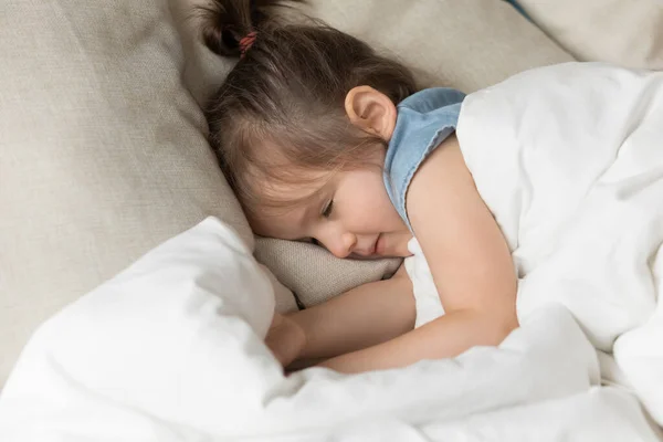 Gadis kecil tidur di tempat tidur di bawah pandangan tertutup yang hangat. — Stok Foto