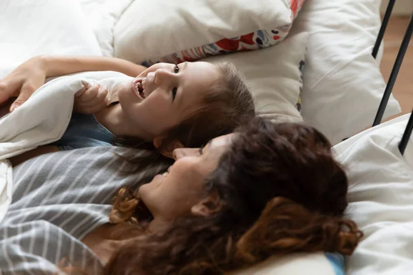 Daughter lying in bed with mother awakens after daytime nap — Stock Photo, Image