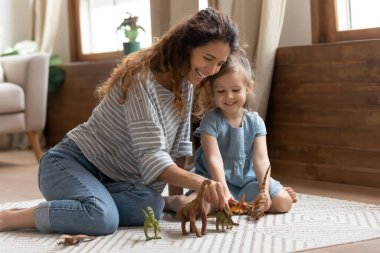 Anne ve çocuk oturma odasında dinozorlarla oynuyor.