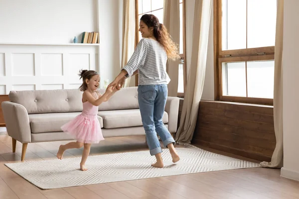 小女儿和妈妈手牵手在客厅里跳舞 — 图库照片