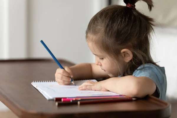 Close-up klein meisje zitten aan bureau houdt potlood tekeningen afbeelding — Stockfoto