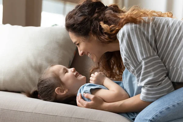 Daughter lying on sofa spend pleasant funny playtime together — ストック写真