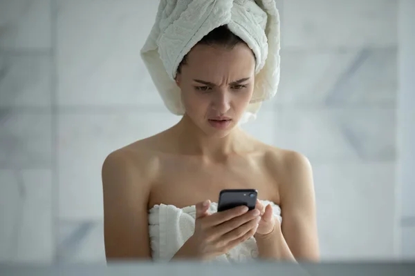 Unhappy young woman reading bad news in message in bathroom — Stock Photo, Image