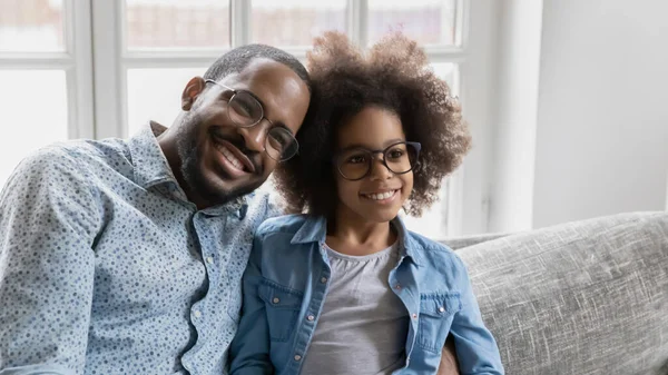 Mosolygó afro-amerikai család szemüvegben ül a kanapén. — Stock Fotó
