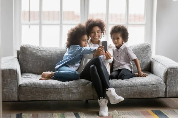 Afroamerikanerin zeigt Kindern lustige Handy-Anwendung. — Stockfoto