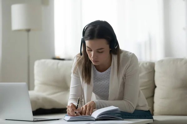 Jongedame in draadloze headset luistert naar online educatieve lezing. — Stockfoto