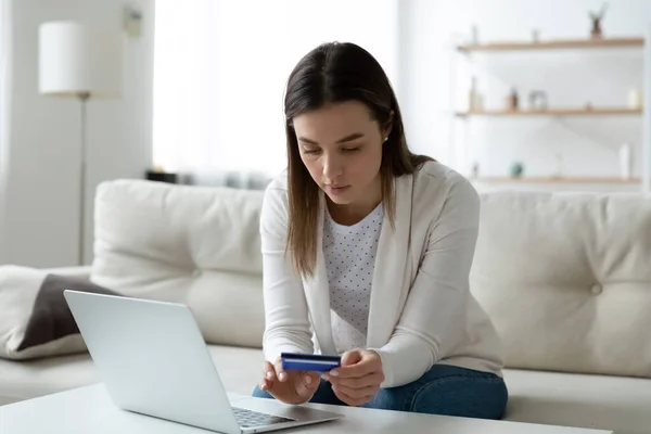 Focused young woman entering banking card information in computer application. — Stock Photo, Image