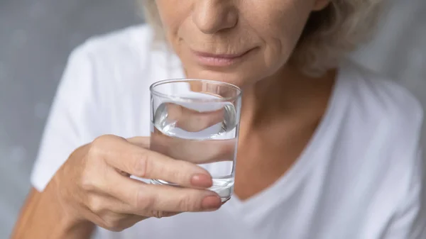 Cerca de la mujer madura sosteniendo un vaso de agua dulce pura — Foto de Stock