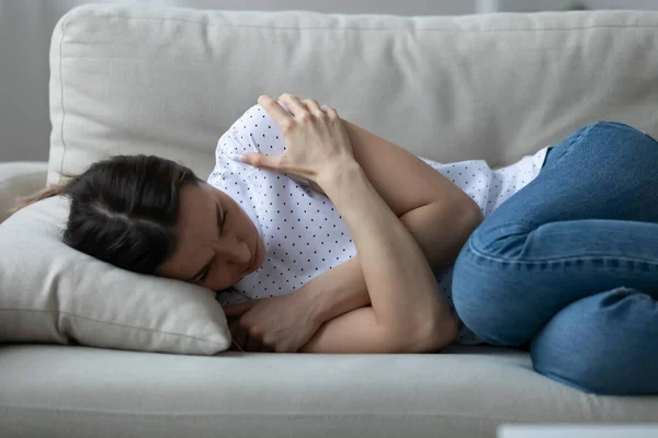 Напряженная молодая женщина лежит на диване, страдая от депрессии. — стоковое фото
