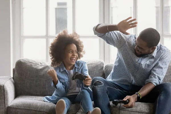 Young biracial father giving high five to daughter, celebrating win. — Stock Photo, Image