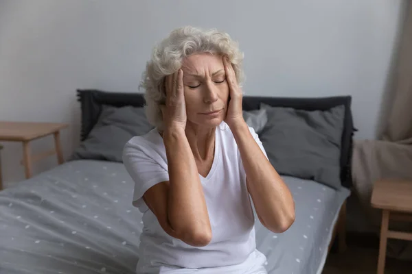 Unzufriedene ungesunde reife Frau, die Schläfen berührt und unter Kopfschmerzen leidet — Stockfoto