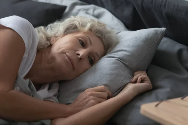 Крупним планом красива зріла жінка лежить в ліжку після пробудження — стокове фото