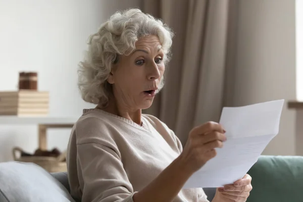 Erstaunt schockiert reife Frau mit offenem Mund Brief lesen — Stockfoto