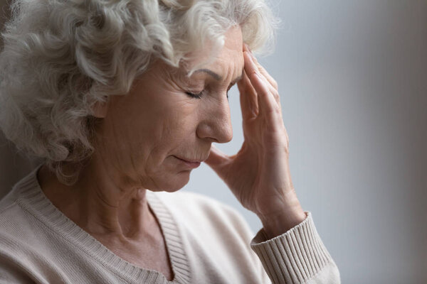 Close up unhappy frustrated mature woman touching forehead, feeling pain