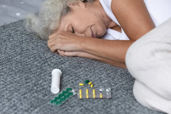 Close up depressed mature woman lying on bed with meds — Stock Photo, Image