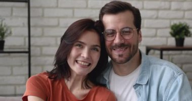 Çekici pozitif çift portresi evde oturmuş kameraya bakarak gülümsüyor.