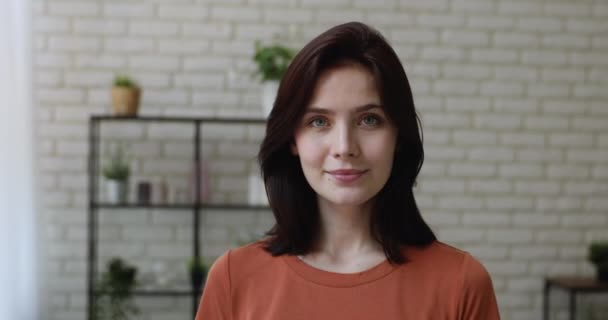 Портрет молодой женщины, стоящей в помещении и улыбающейся, позирующей перед камерой — стоковое видео