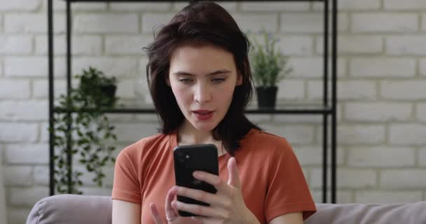 女人坐在沙发上，智能手机在网上用电子商务购物 — 图库视频影像