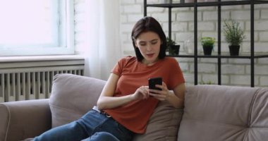 25 'li yaşlardaki kadınlar koltukta rahatlar. Akıllı telefonlar sosyal medyada kayar.