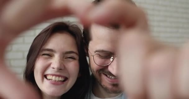 Retrato de primer plano de pareja feliz unir los dedos haciendo forma de corazón — Vídeos de Stock
