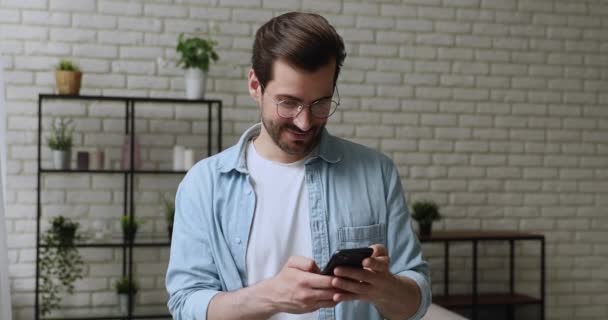 Millennial guy holding smartphone having fun use internet fun services — Stockvideo