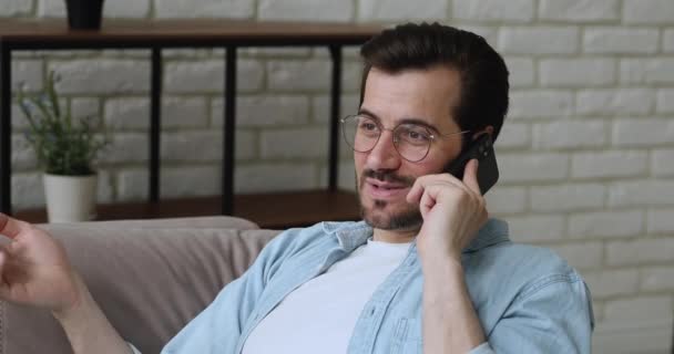 El hombre usa el teléfono inteligente hablando con un amigo resuelve negocios desde casa — Vídeos de Stock