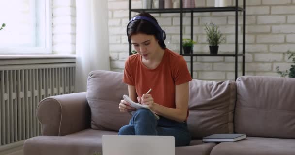Γυναίκα ακούει ήχο μέσω ασύρματων ακουστικών γράφοντας μελέτη στο σπίτι — Αρχείο Βίντεο