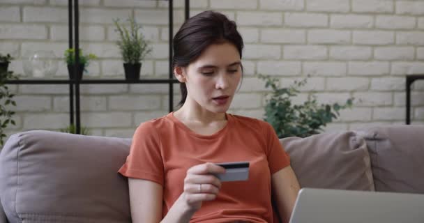 소파에 앉아 컴퓨터 신용 카드를 사용하는 여자 — 비디오
