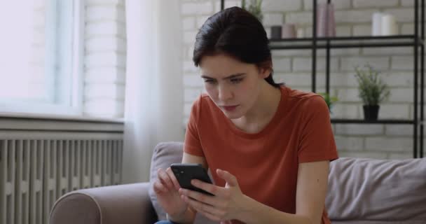 스마트폰을 사용하여 집안에 앉아 있는 여자가 나쁜 소식을 읽고 기분 이상 한다 — 비디오