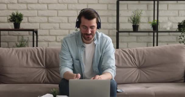 Mann mit Kopfhörer unterhält sich per Videoanruf angenehm distanziert — Stockvideo